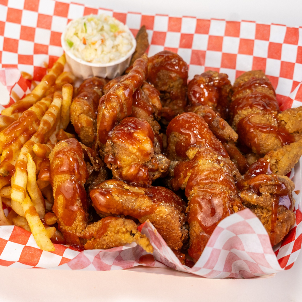 Crispy fried chicken wings drizzled with barbecue sauce, served with crinkle-cut fries and coleslaw.