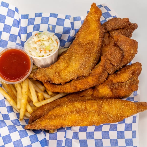 Crispy fried fish and chicken tenders served with fries, coleslaw, and red dipping sauce on blue-and-white checkered paper.