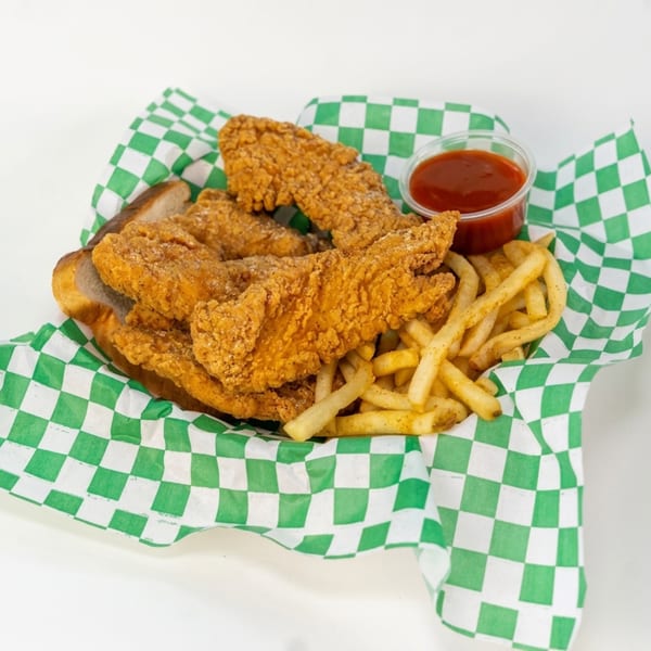 Crispy fried chicken tenders, french fries, and a side of ketchup in a green and white checkered basket.